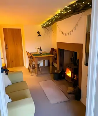 a living room with a table and a fireplace at Cozy Cottage in Caldbeck in Caldbeck