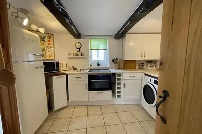 a kitchen with white cabinets and a washer and dryer at Cozy Cottage in Caldbeck in Caldbeck