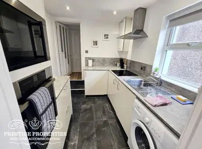 a kitchen with a sink and a washing machine at Moon Cottage By Prestige Properties SA in Egremont