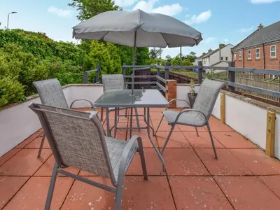 a patio with a table and chairs and an umbrella at Station House in St Bees