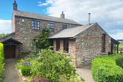 an old stone house with a garden in front of it at Unique schoolhouse in the peaceful Western Lakes in Bootle