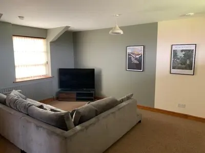 a living room with a couch and a flat screen tv at Unique schoolhouse in the peaceful Western Lakes in Bootle