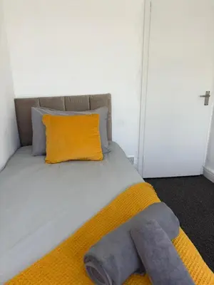 a bed with an orange pillow and a yellow blanket at Modern 3BR House Near Manchester-Parking Included in Moffat