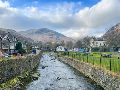 a river in a town with mountains in the background at Rattlebeck Cottage in Glenridding