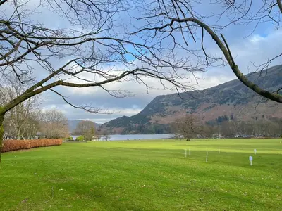 a green field with a lake and mountains in the background at Rattlebeck Cottage in Glenridding