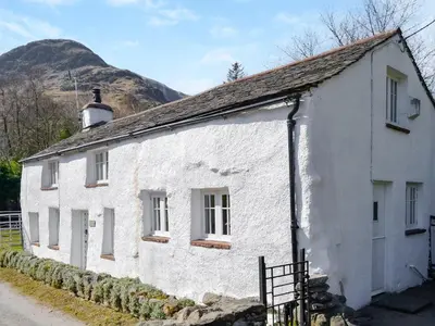 a white house with a mountain in the background at Rattlebeck Cottage in Glenridding