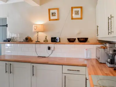 a kitchen with white cabinets and a wooden counter top at Rattlebeck Cottage in Glenridding