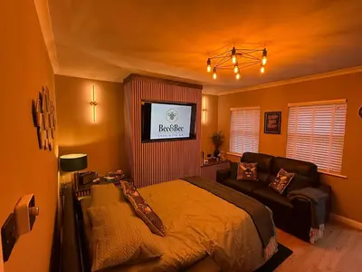 a bedroom with a bed and a couch and a tv at Modern House Maryport Sleeps 6 in Maryport