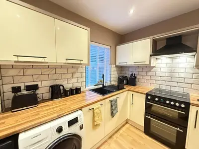 a kitchen with white cabinets and a washer and dryer at Modern House Maryport Sleeps 6 in Maryport