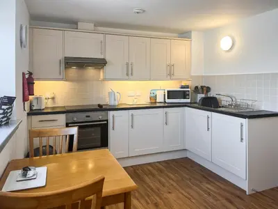 a kitchen with white cabinets and a wooden table at Ninians Landing in Kirkcudbright