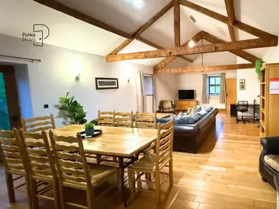 a dining room with a table and a couch at Old Corner Barn Lake District Escape by PolkaStays in Penrith