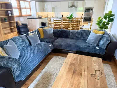 a living room with a blue couch and a wooden table at Old Corner Barn Lake District Escape by PolkaStays in Penrith