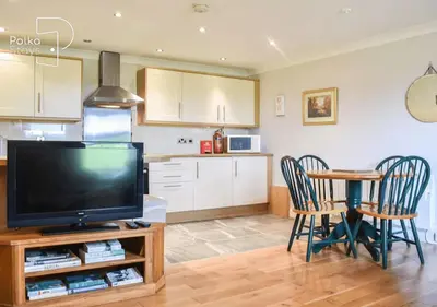 a living room with a television and a table with chairs at Crag Barn Cottage Lake District by PolkaStays in Penrith