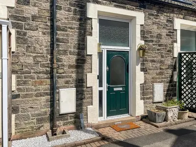 a green door on the side of a brick house at Three Chapel Court in Cockermouth