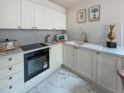 a kitchen with white cabinets and a stove top oven at Three Chapel Court in Cockermouth