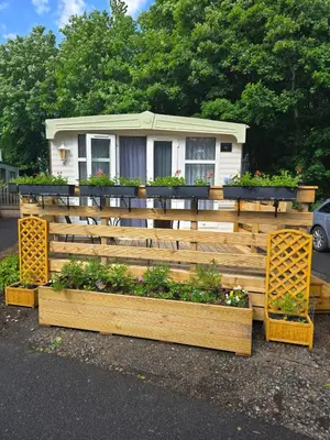 a house with a wooden fence and some plants at Woodlands Retreat Holiday Home in Ballantrae