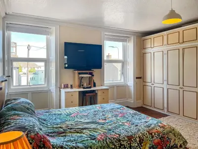 a bedroom with a bed and a desk and two windows at Midtown House in Aspatria