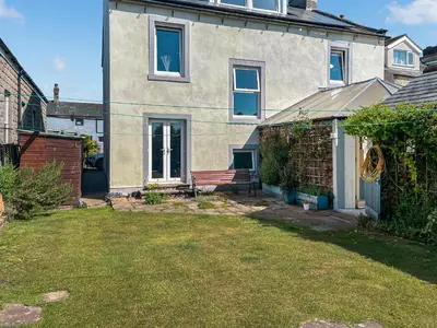 a house with a bench in front of a yard at Midtown House in Aspatria