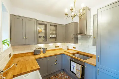 a kitchen with blue cabinets and wooden counter tops at Penninghame Estate - West Lodge in Challoch