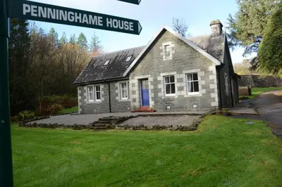 a stone house with a blue door and a street sign at Penninghame Estate - West Lodge in Challoch