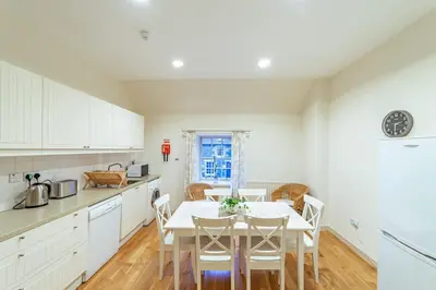 a kitchen with white cabinets and a table and chairs at Penninghame Estate - Bruce Apartment in Challoch