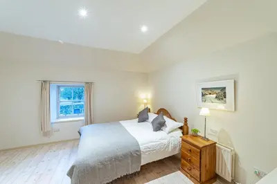 a white bedroom with a bed and a window at Penninghame Estate - Bruce Apartment in Challoch