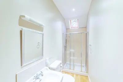 a white bathroom with a shower and a sink at Penninghame Estate - Bruce Apartment in Challoch