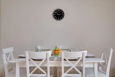 a white table with chairs and a clock on a wall at Penninghame Estate - Wallace Apartment in Challoch