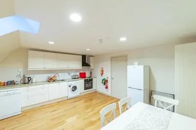 a kitchen with a table and a white refrigerator at Penninghame Estate - Wallace Apartment in Challoch