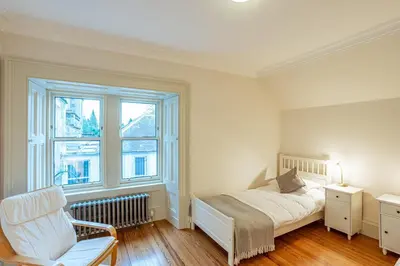 a bedroom with a bed and a chair and a window at Penninghame Estate - Stewart Apartment in Challoch