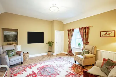 a living room with two chairs and a flat screen tv at Penninghame Estate- Gardeners Cottage in Challoch