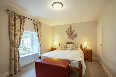 a bedroom with a bed and a window at Penninghame Estate- Gardeners Cottage in Challoch