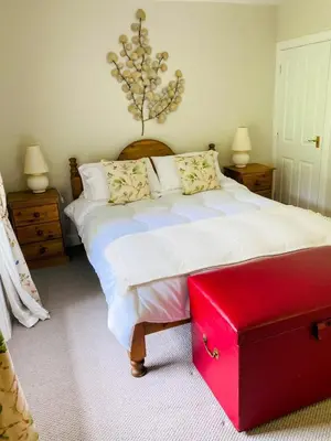 a bedroom with a bed with a red trunk on it at Penninghame Estate- Gardeners Cottage in Challoch