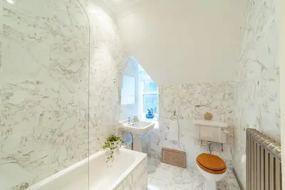 a bathroom with a tub and a toilet and a sink at Penninghame Estate - Tower Apartment in Challoch