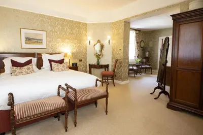 a bedroom with a large bed with two benches at Knockinaam Lodge in Portpatrick