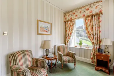 a room with two chairs and a table and a window at Knockinaam Lodge in Portpatrick