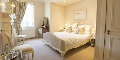 a bedroom with a white bed and a window at Knockinaam Lodge in Portpatrick
