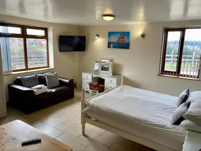 a bedroom with a bed and a couch and a tv at Folly gardens in Moffat