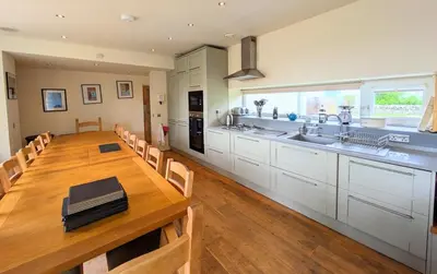 a kitchen with a wooden table and a large kitchen at The Coach House at Durhamhill with llamas & games room mini cinema in Kirkpatrick Durham
