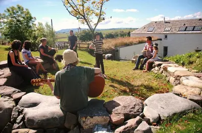 a group of people sitting around a rock wall at The Coach House at Durhamhill with llamas & games room mini cinema in Kirkpatrick Durham