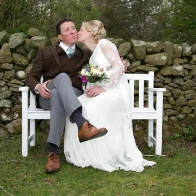 a bride and groom sitting on a bench at The Coach House at Durhamhill with llamas & games room mini cinema in Kirkpatrick Durham