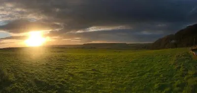 a sunset in a field with the sun setting at Sycamore Cottage, Western Lakes Bolthole With Views Across the Fells in Arlecdon