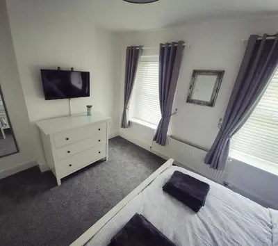 a bedroom with a bed and a dresser and a television at Sycamore Cottage, Western Lakes Bolthole With Views Across the Fells in Arlecdon