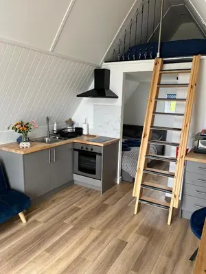 a kitchen with a stairs leading to a bunk bed at Tiny home on an organic croft, Isle of Arran in Kildonan