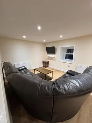 a black leather couch in a living room with a tv at Ballavelt in Isle of Man