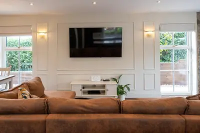 a living room with a brown couch and a tv at Our Cosy Cottage in Gatehouse of Fleet