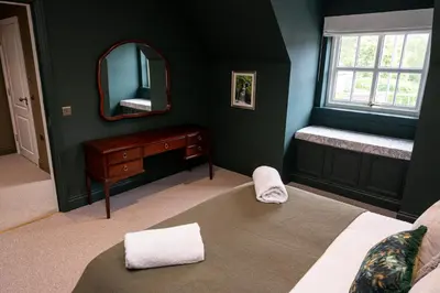 a bedroom with a mirror and a bed and a dresser at Our Cosy Cottage in Gatehouse of Fleet