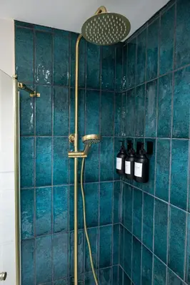 a bathroom with a shower with blue tiles at Our Cosy Cottage in Gatehouse of Fleet