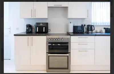 a kitchen with white cabinets and a stove top oven at Central Mews Free Wi-Fi-Parking-Contractors in Newton Stewart