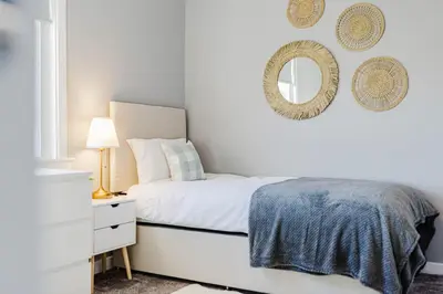 a white bedroom with a bed and a mirror at Welcoming Home in Hurlford, Kilmarnock - Bonnie Lodgings in Hurlford